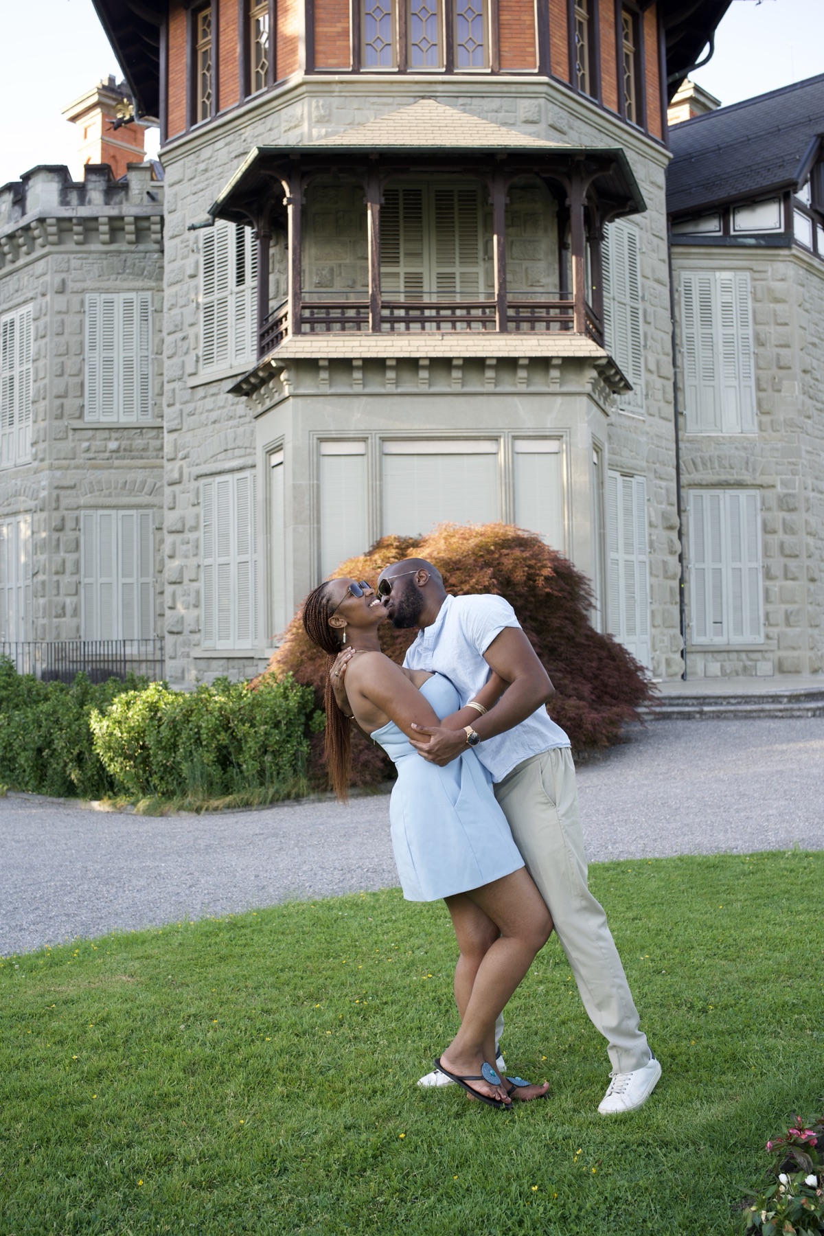 Adetunji dipping Sally into a kiss on the lawn before the turret of Villa Dreilinden